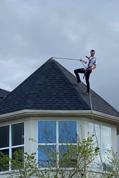 Roofer tied off on a steep pyramid roof with a safety rope